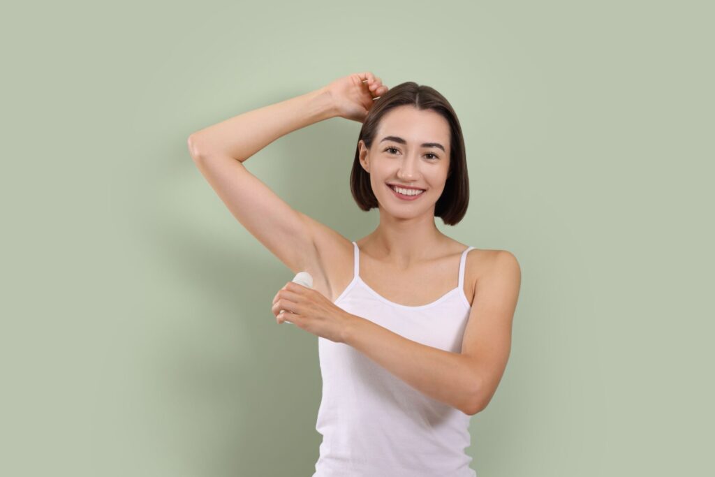 Smiling,Woman,Applying,Roll on,Deodorant,On,Green,Background