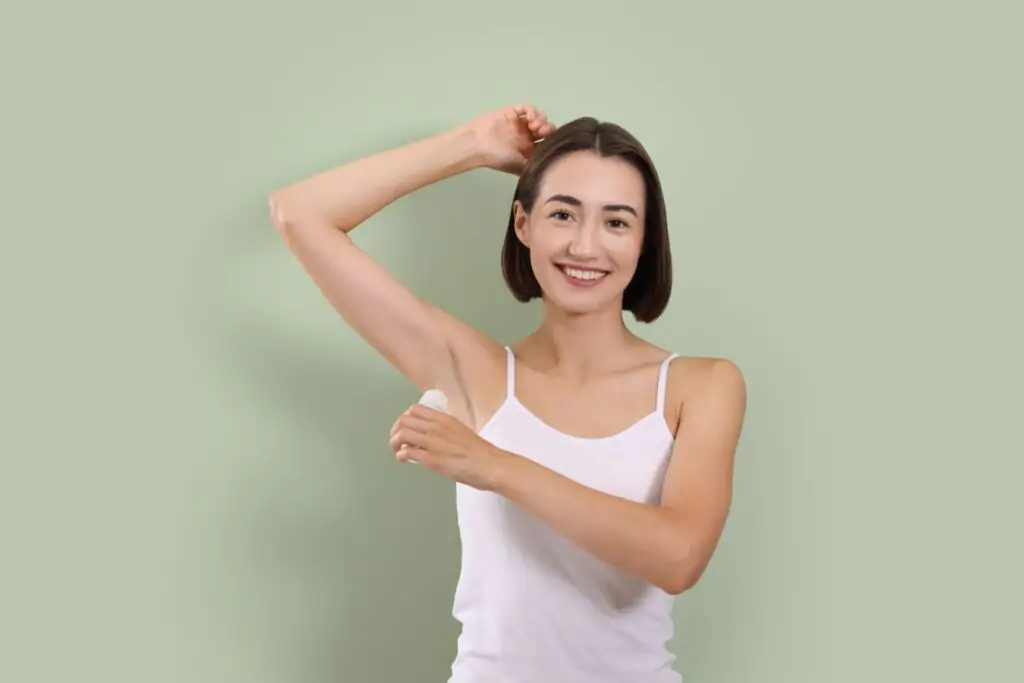 Smiling,Woman,Applying,Roll on,Deodorant,On,Green,Background